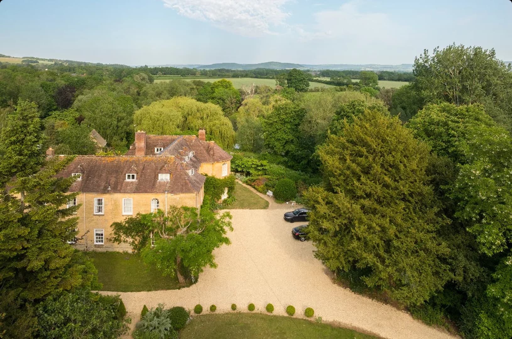 Aerial view of the Upper Court manor house, gravel drive and wooded grounds