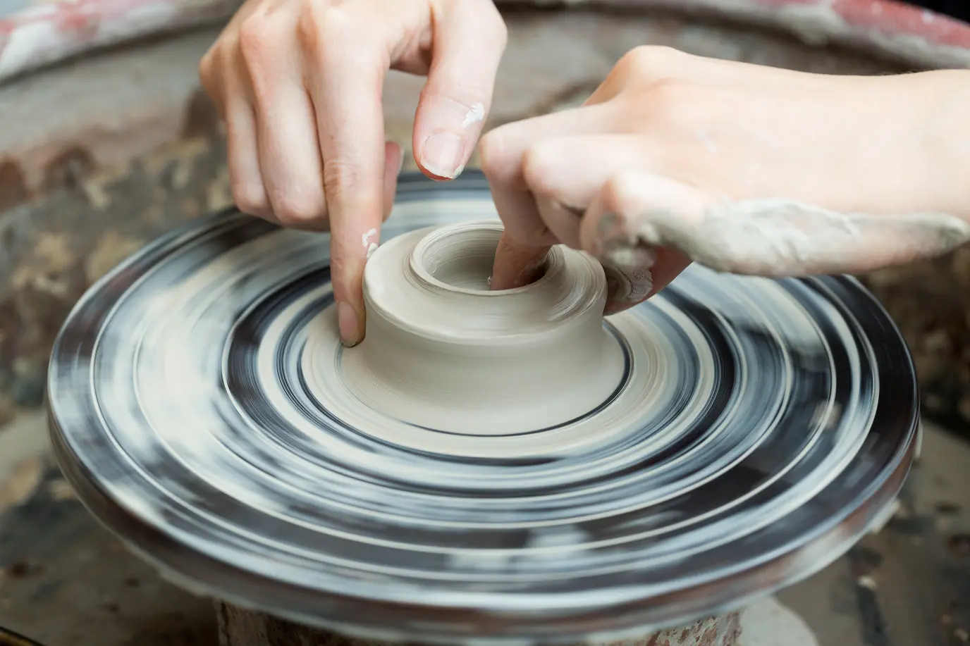 Hands shaping clay on a pottery wheel